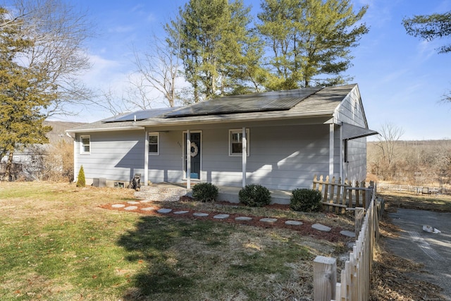 ranch-style home with covered porch, a front lawn, and solar panels