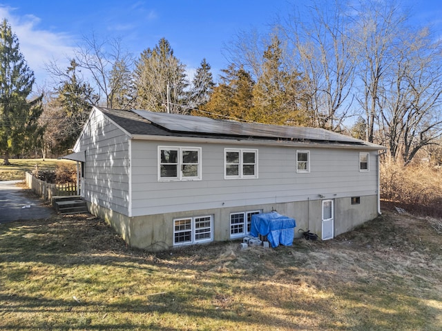 back of property with a yard and solar panels