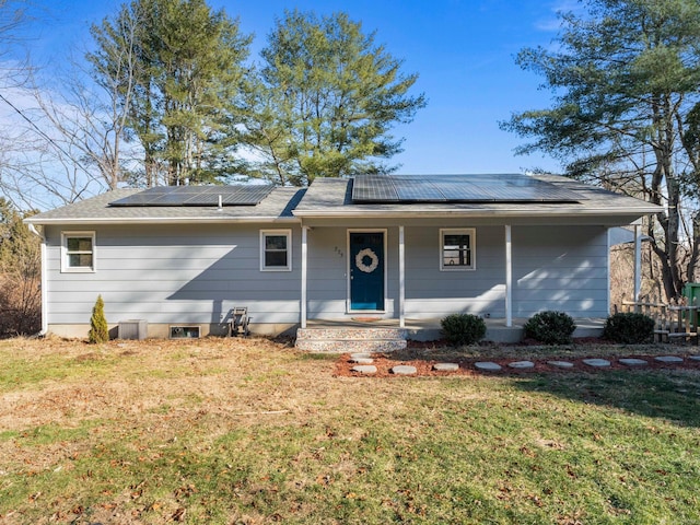 ranch-style home with a porch, solar panels, and a front yard