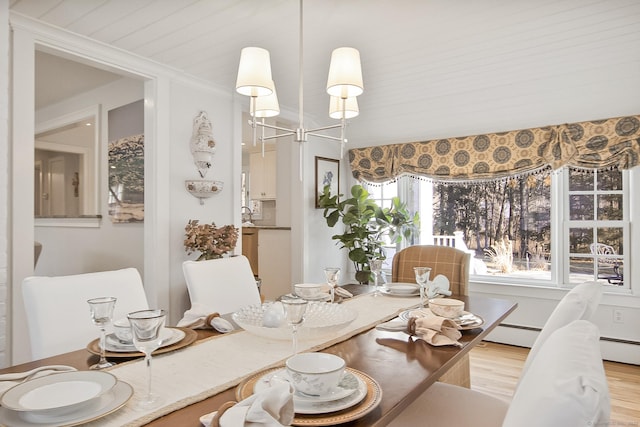 dining room with light wood-type flooring, crown molding, and a baseboard radiator