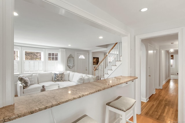 kitchen featuring a kitchen breakfast bar, light hardwood / wood-style floors, and light stone counters