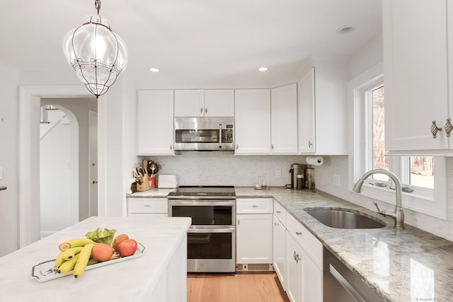 kitchen with white cabinetry, appliances with stainless steel finishes, decorative light fixtures, a chandelier, and sink