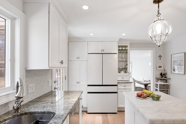 kitchen featuring light stone countertops, white refrigerator, white cabinetry, and sink