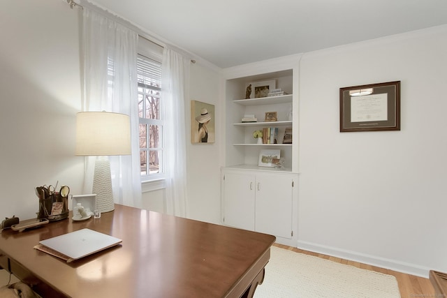 office with light wood-type flooring, built in features, and crown molding