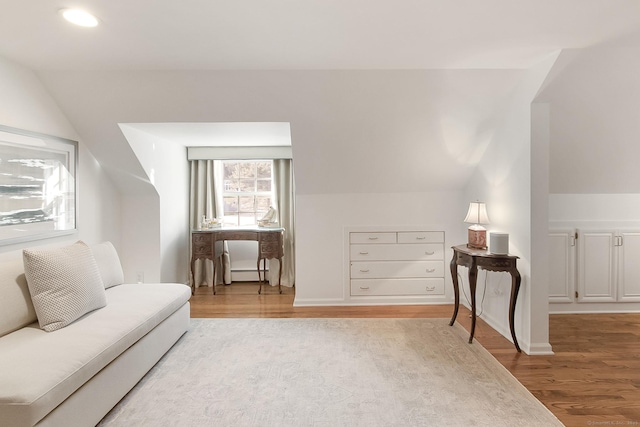 living area featuring lofted ceiling, a baseboard heating unit, and hardwood / wood-style floors