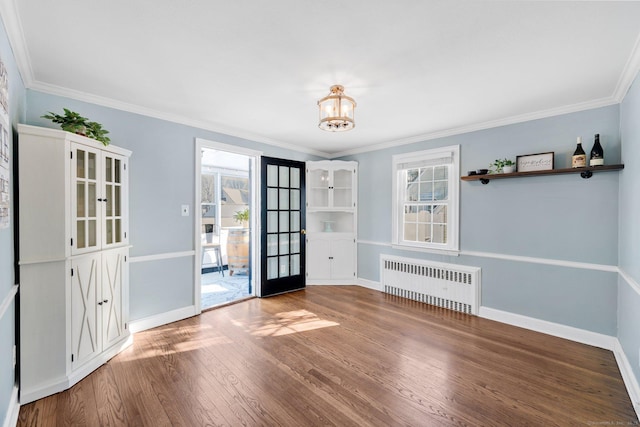 unfurnished room with wood-type flooring, radiator, and crown molding