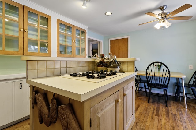 kitchen featuring tasteful backsplash, ceiling fan, a kitchen island, hardwood / wood-style floors, and white gas cooktop