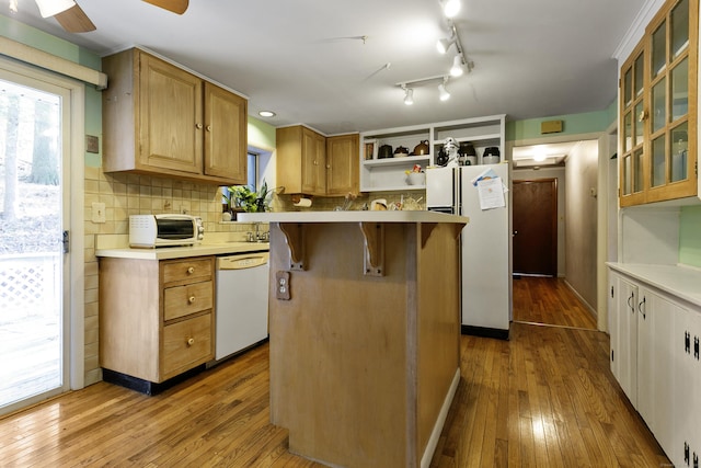 kitchen featuring white appliances, a center island, decorative backsplash, light wood-type flooring, and ceiling fan