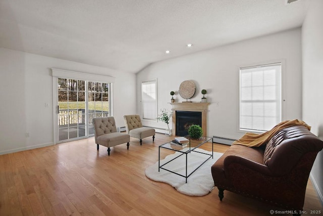 living room featuring light hardwood / wood-style flooring, vaulted ceiling, and baseboard heating