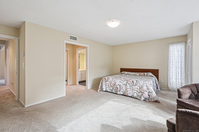 bedroom featuring connected bathroom and light carpet