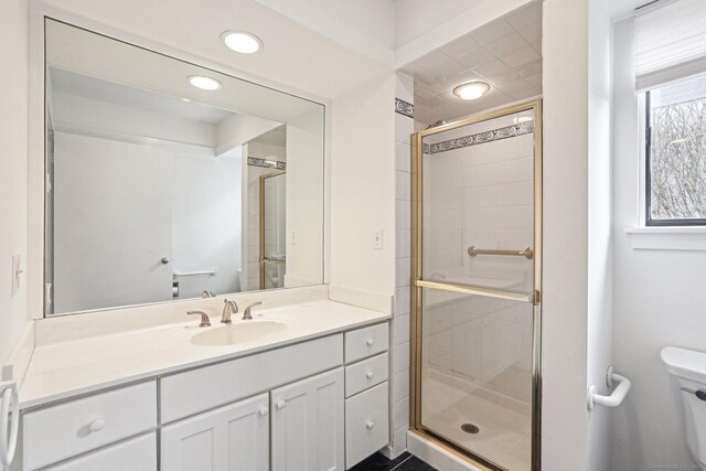 bathroom with toilet, an enclosed shower, and vanity