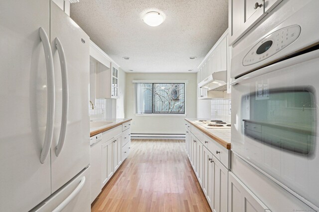 kitchen featuring white appliances, white cabinets, decorative backsplash, a baseboard radiator, and light wood-type flooring