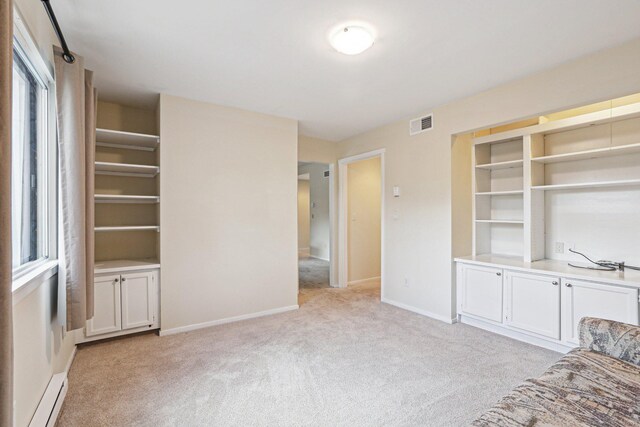 unfurnished living room with light colored carpet and a baseboard heating unit