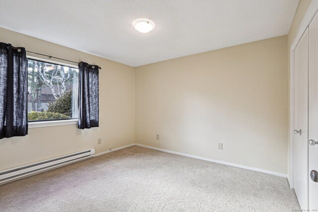 unfurnished bedroom featuring carpet floors, baseboard heating, and a closet