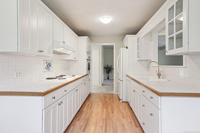 kitchen with white appliances, a textured ceiling, light hardwood / wood-style flooring, white cabinetry, and sink