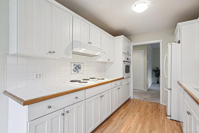 kitchen with white cabinetry, tile counters, white appliances, and light hardwood / wood-style flooring