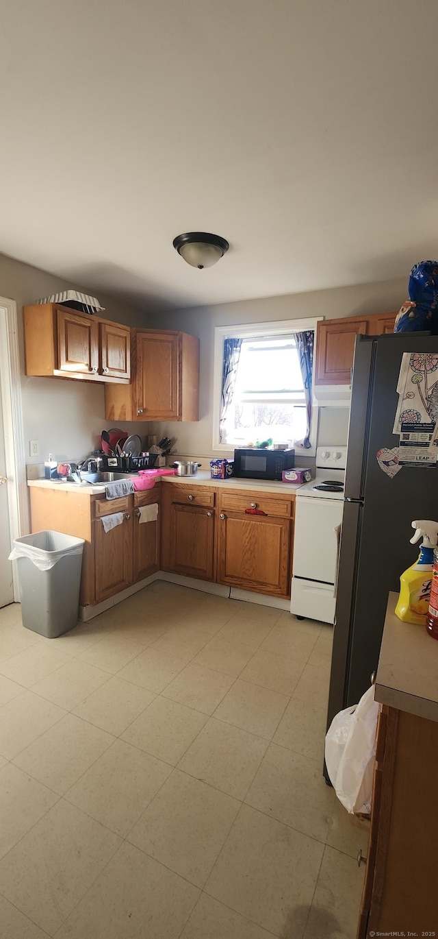 kitchen featuring white electric stove and stainless steel refrigerator