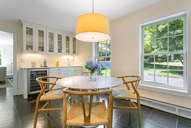 dining room with indoor wet bar, wine cooler, a baseboard radiator, and plenty of natural light