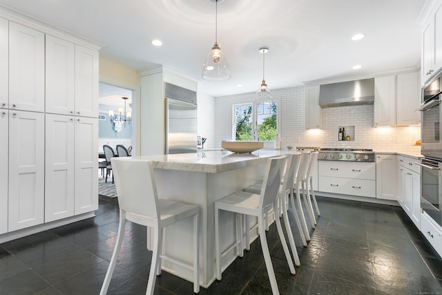 kitchen with decorative light fixtures, white cabinets, tasteful backsplash, wall chimney range hood, and appliances with stainless steel finishes