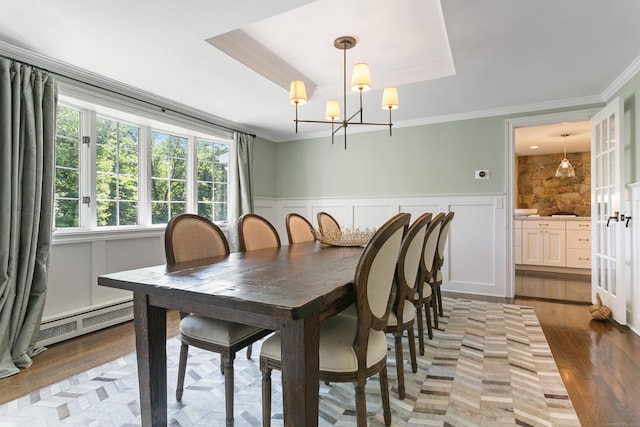 dining area featuring baseboard heating, a raised ceiling, and crown molding