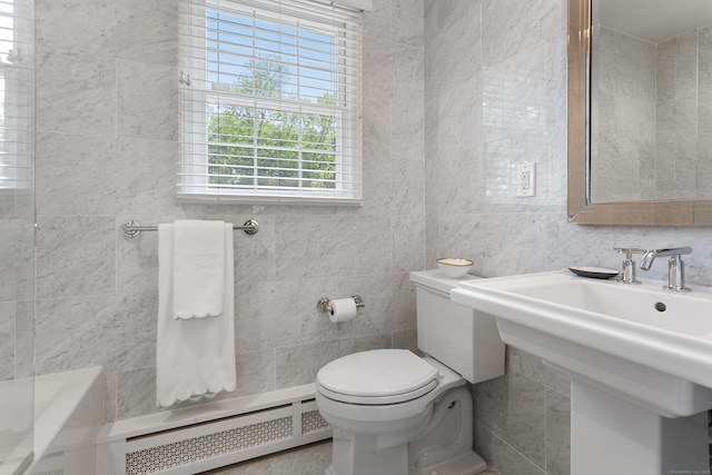 bathroom featuring toilet, a washtub, a baseboard radiator, and tile walls