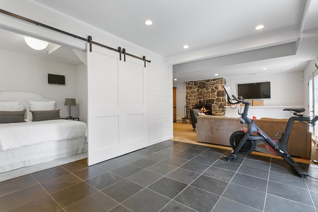 exercise area with a barn door and a stone fireplace