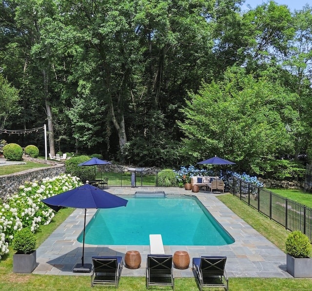 view of pool with an outdoor living space, a diving board, and a patio area