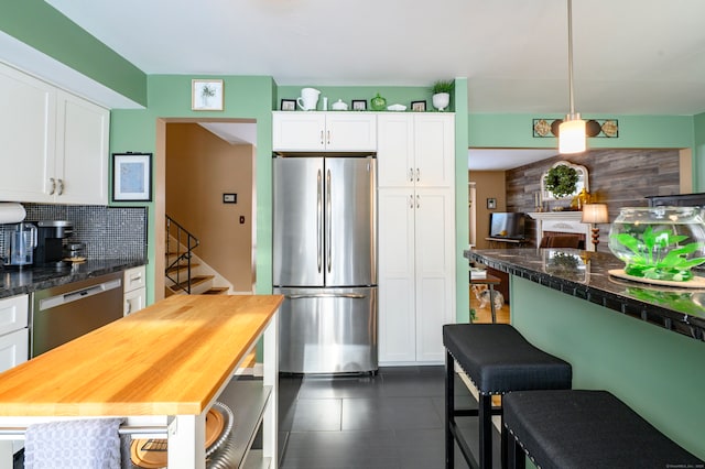 kitchen with decorative backsplash, decorative light fixtures, white cabinets, and stainless steel appliances