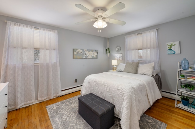 bedroom with ceiling fan, a baseboard heating unit, and light hardwood / wood-style flooring