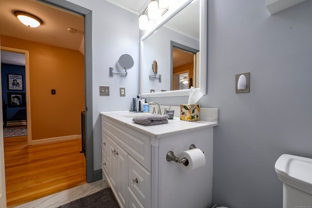 bathroom with vanity, toilet, crown molding, and hardwood / wood-style flooring