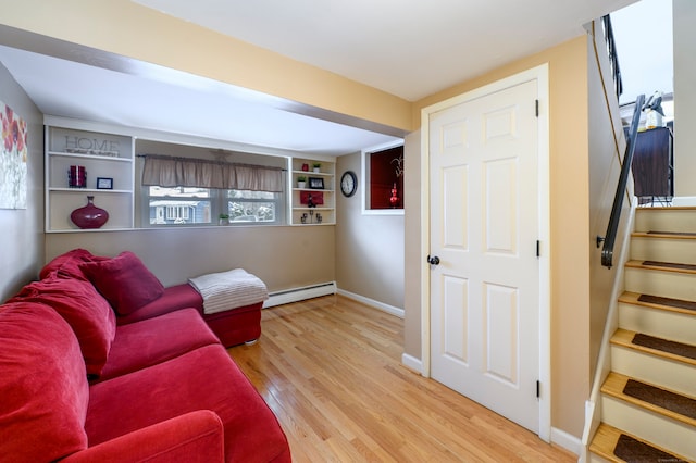 living room with a baseboard radiator, light wood-type flooring, and built in features