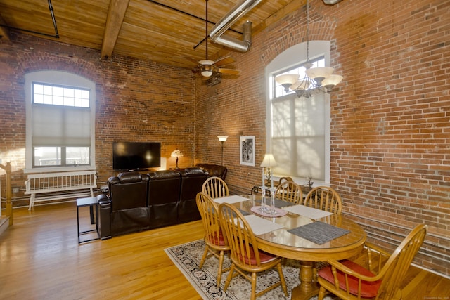 dining area featuring a high ceiling, brick wall, wooden ceiling, and beamed ceiling