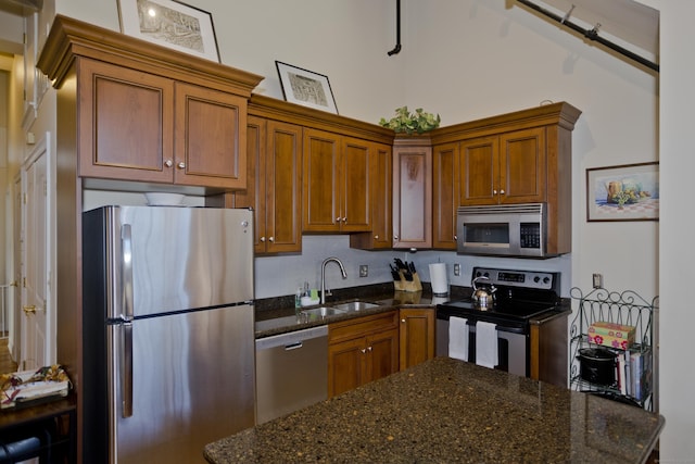 kitchen featuring appliances with stainless steel finishes, dark stone countertops, and sink