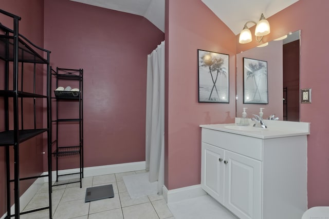 bathroom with tile patterned flooring, vaulted ceiling, and vanity