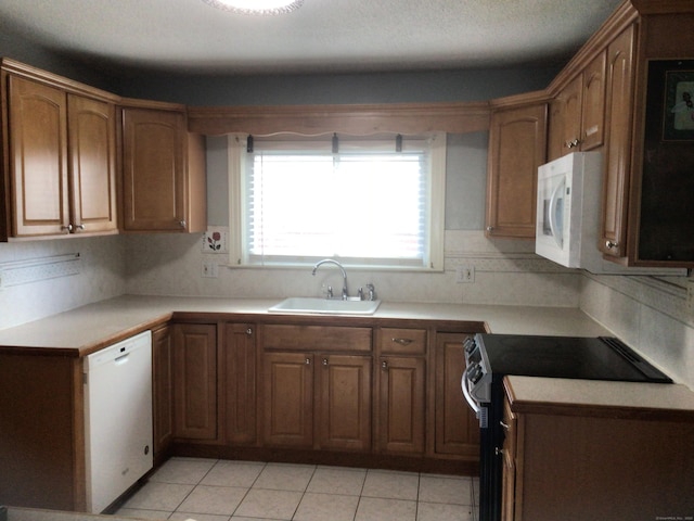 kitchen featuring light countertops, white appliances, a sink, and brown cabinets