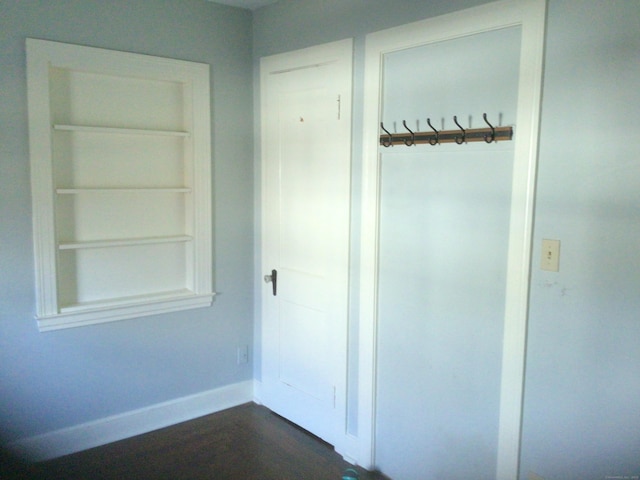 interior space featuring built in shelves, baseboards, and dark wood-style flooring