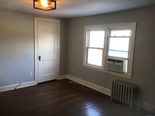 empty room featuring radiator, cooling unit, and dark hardwood / wood-style floors