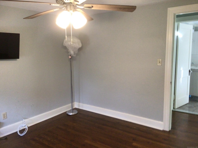 unfurnished room with baseboards, dark wood finished floors, and a ceiling fan