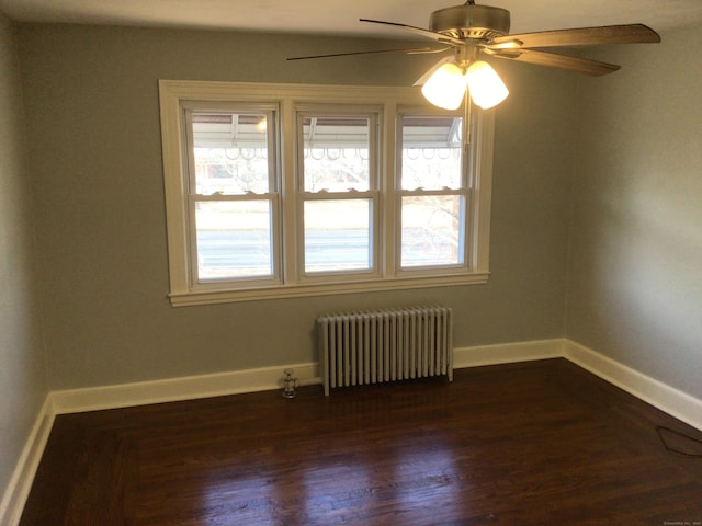 unfurnished room with baseboards, dark wood finished floors, radiator heating unit, and ceiling fan