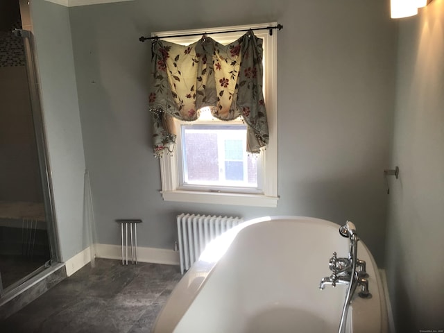 bathroom featuring radiator heating unit and a tub to relax in