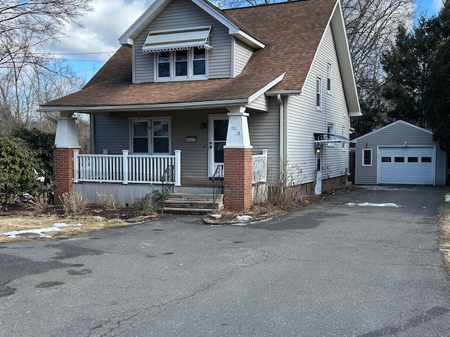 view of front of house featuring aphalt driveway, an outbuilding, a porch, a shingled roof, and a garage