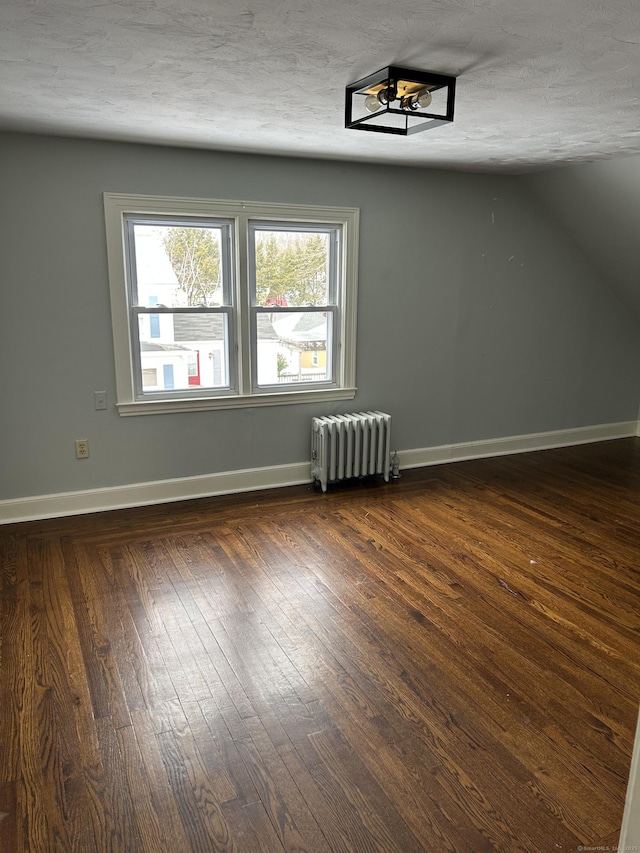 spare room featuring baseboards, dark wood-style flooring, a textured ceiling, and radiator