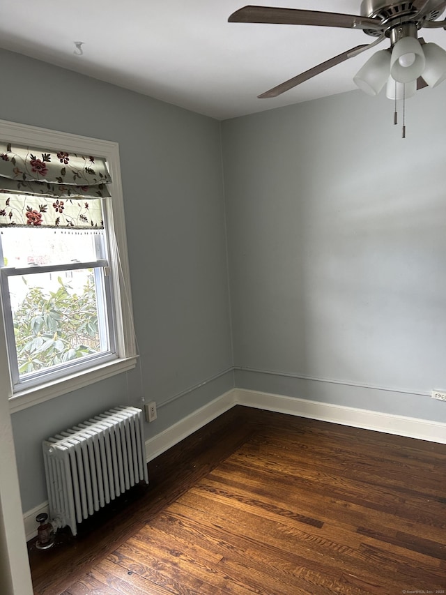 unfurnished room with dark wood-type flooring, radiator, and baseboards