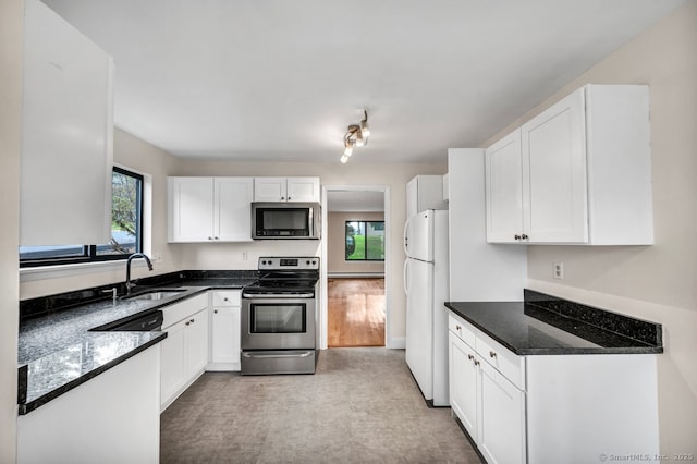 kitchen featuring sink, white cabinetry, dark stone countertops, and stainless steel appliances