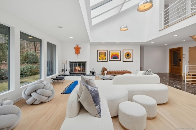 living room featuring high vaulted ceiling and a skylight