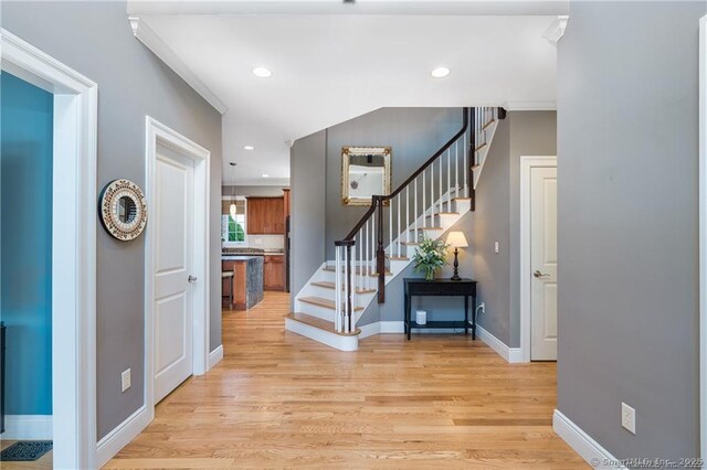 foyer entrance featuring light hardwood / wood-style flooring and crown molding