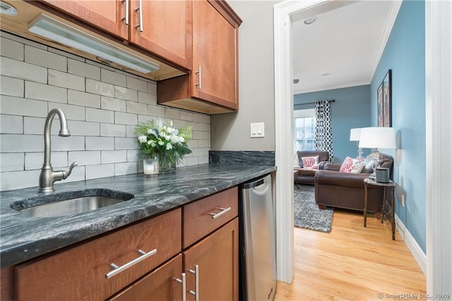 kitchen with light hardwood / wood-style floors, tasteful backsplash, dark stone countertops, crown molding, and sink