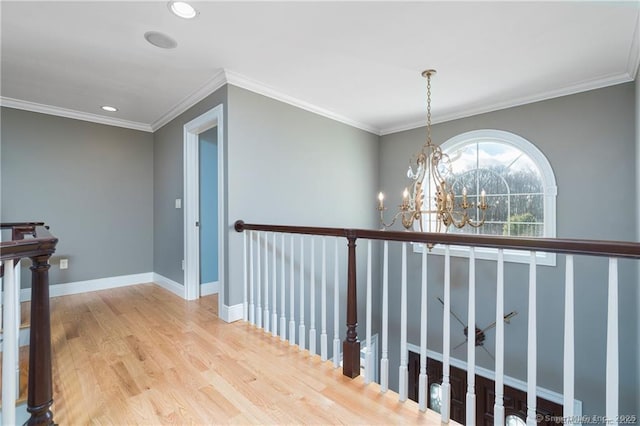 hallway with hardwood / wood-style floors, ornamental molding, and a chandelier