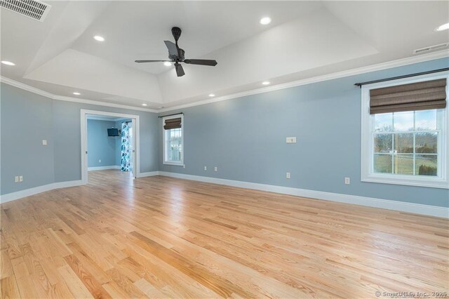 unfurnished room featuring light wood-type flooring, ceiling fan, crown molding, and a tray ceiling