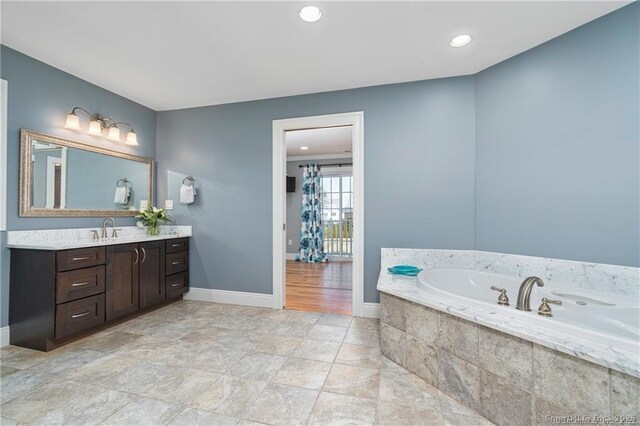 bathroom featuring vanity and a relaxing tiled tub